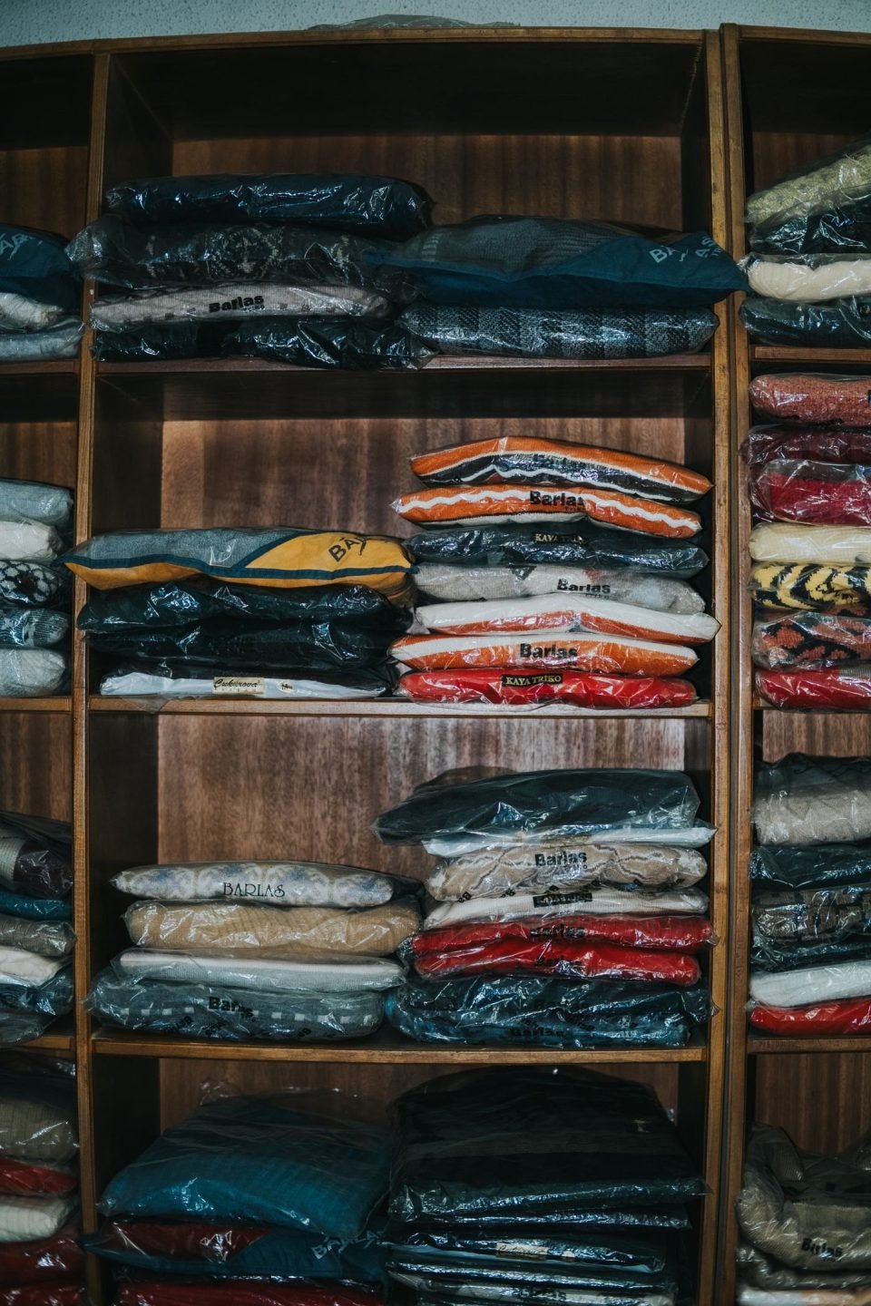 Clothing neatly arranged on shelves, each item wrapped in plastic