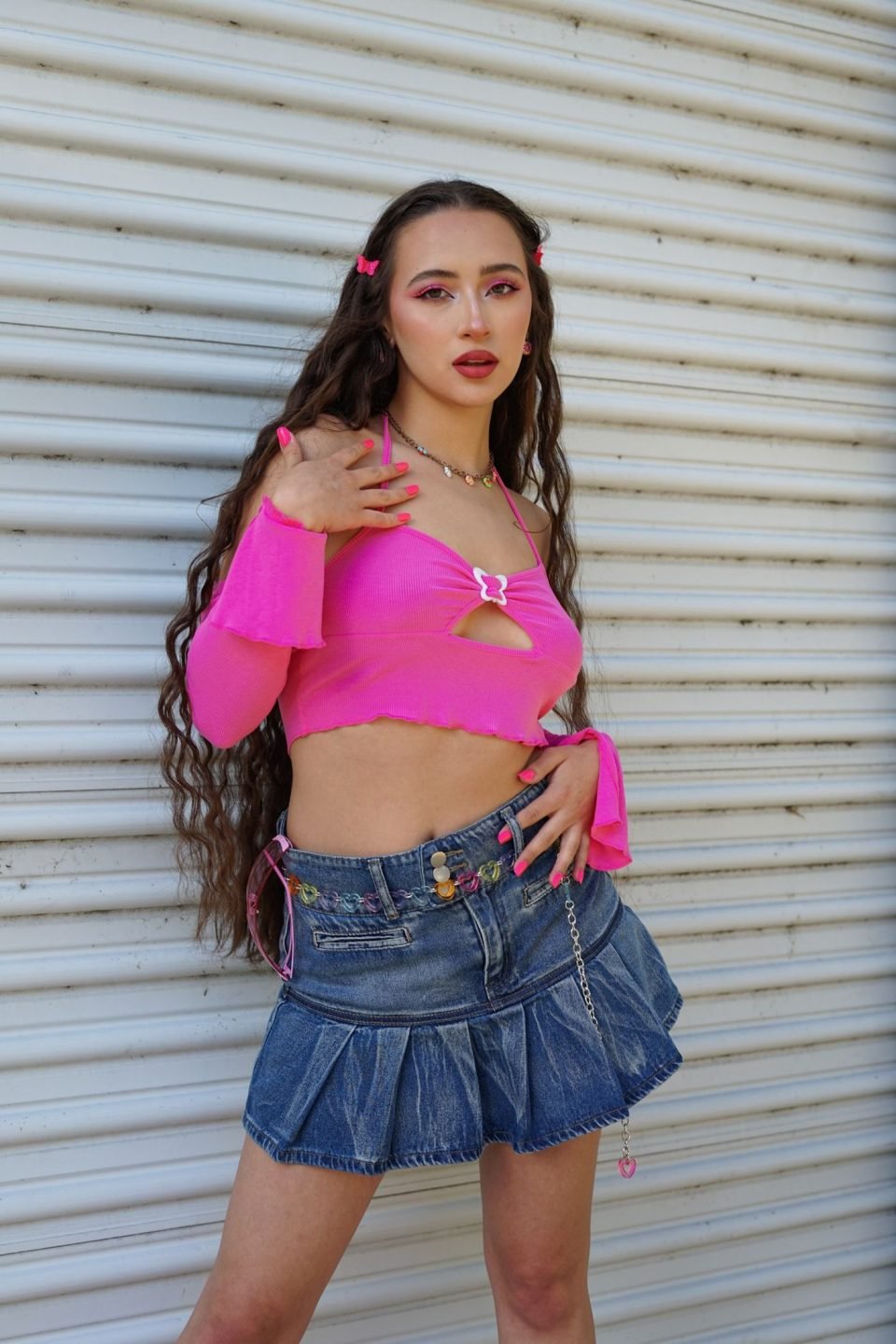 A young woman in a pink crop top and denim skirt, a Y2K style outfit